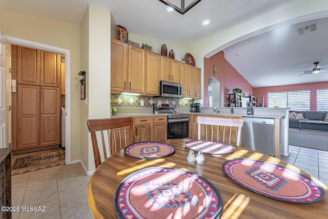 kitchen featuring tasteful backsplash, light tile patterned flooring, kitchen peninsula, and appliances with stainless steel finishes