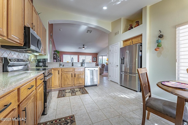 kitchen featuring appliances with stainless steel finishes, lofted ceiling, sink, light tile patterned floors, and ceiling fan