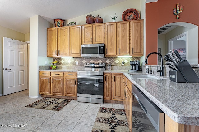 kitchen with sink, light tile patterned floors, stainless steel appliances, and backsplash