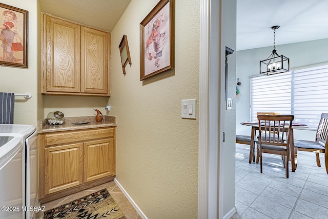 kitchen featuring light tile patterned flooring, washing machine and clothes dryer, decorative light fixtures, and an inviting chandelier