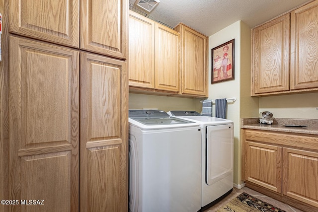 washroom with washing machine and dryer, cabinets, and a textured ceiling