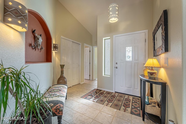 foyer with high vaulted ceiling and light tile patterned floors