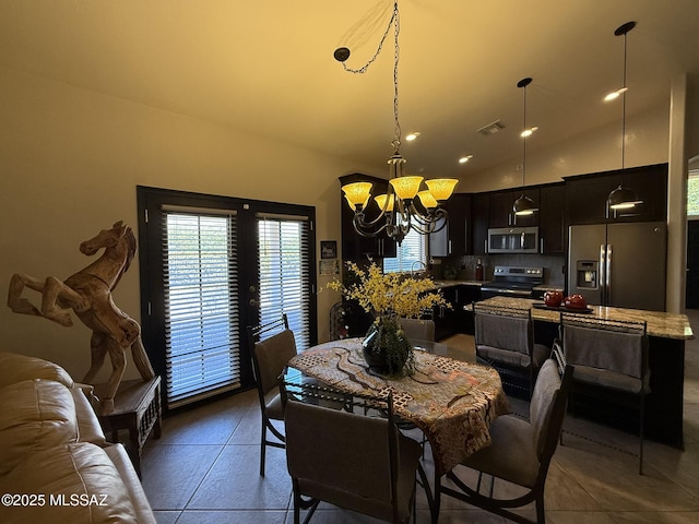 dining area featuring french doors, a chandelier, dark tile patterned flooring, and lofted ceiling