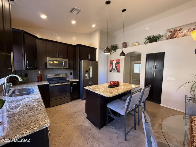 kitchen with light tile patterned floors, sink, a kitchen island, decorative light fixtures, and stainless steel appliances