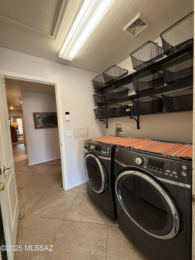 laundry area featuring washing machine and dryer and light tile patterned floors