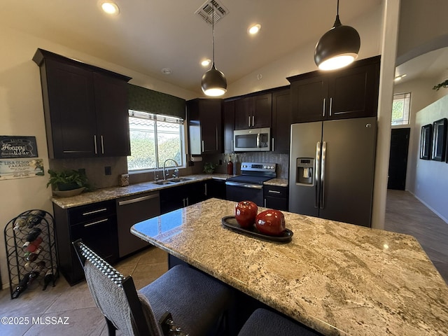 kitchen featuring sink, hanging light fixtures, appliances with stainless steel finishes, and light stone counters