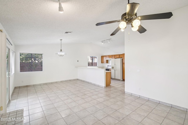 interior space featuring ceiling fan with notable chandelier, vaulted ceiling, a textured ceiling, and light tile patterned flooring