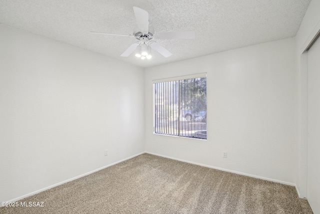 carpeted spare room featuring ceiling fan and a textured ceiling