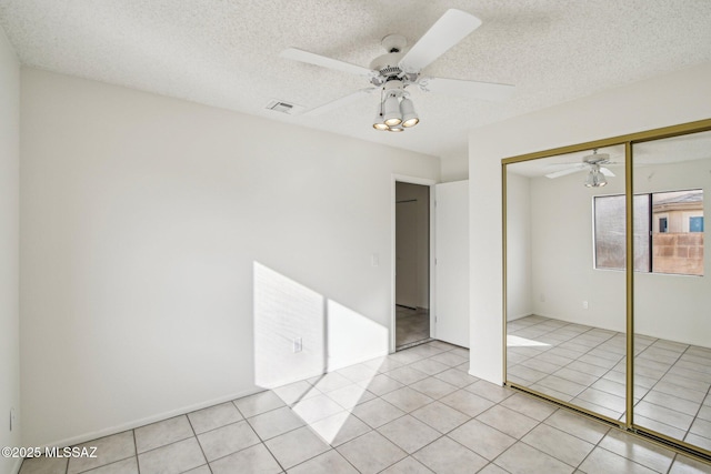 unfurnished bedroom featuring light tile patterned floors, a textured ceiling, a closet, and ceiling fan