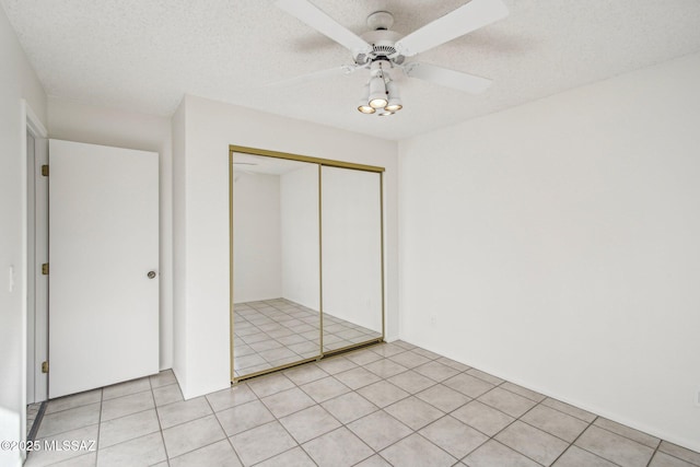 unfurnished bedroom featuring ceiling fan, a textured ceiling, a closet, and light tile patterned floors