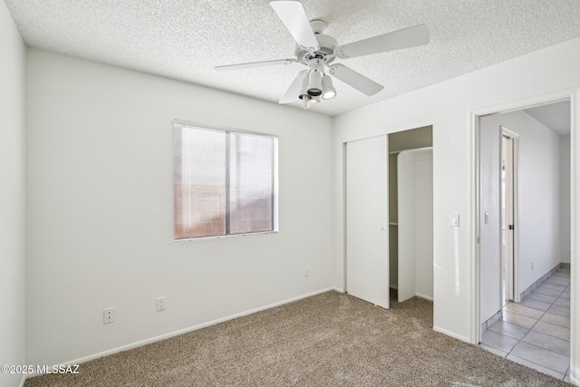 unfurnished bedroom with ceiling fan, light carpet, a textured ceiling, and a closet