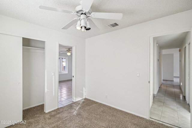 unfurnished bedroom featuring ceiling fan, carpet flooring, a closet, and a textured ceiling