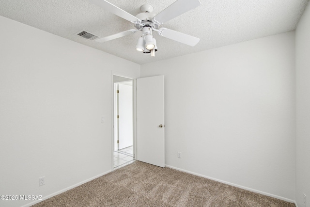 carpeted empty room with ceiling fan and a textured ceiling