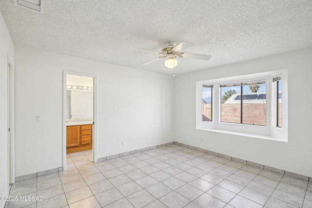 spare room featuring light tile patterned flooring, ceiling fan, and a textured ceiling