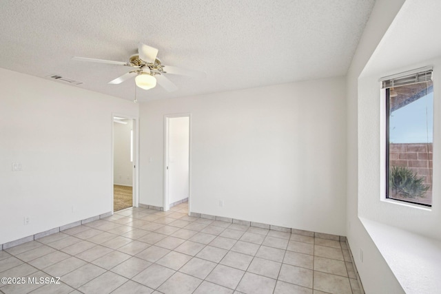 empty room with light tile patterned flooring, a textured ceiling, and ceiling fan