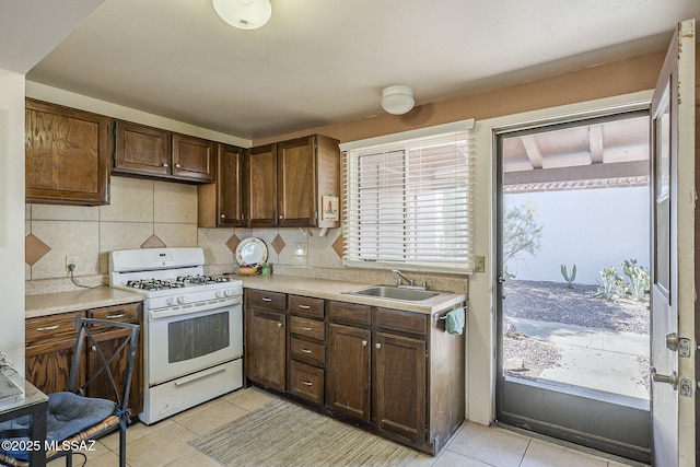 kitchen featuring a sink, decorative backsplash, gas range gas stove, and light countertops