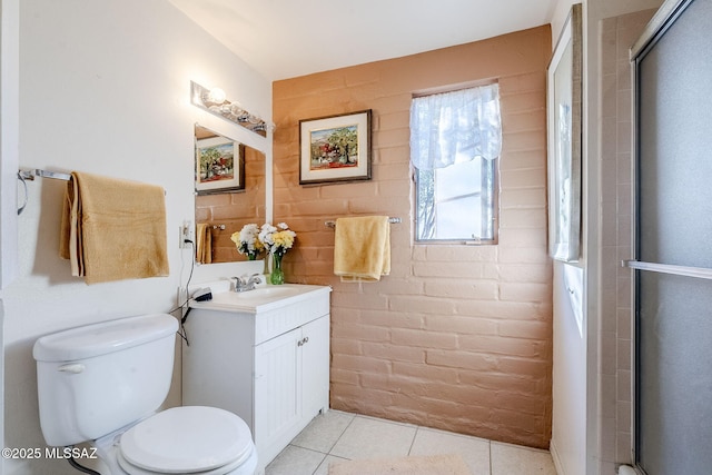 bathroom featuring toilet, brick wall, vanity, and a shower with shower door