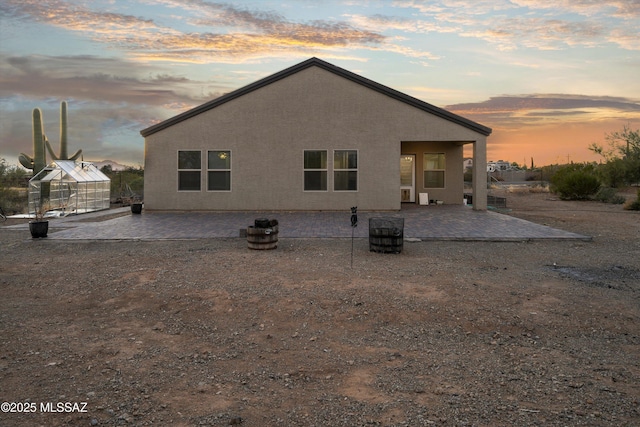 back house at dusk with an outdoor structure, a patio, and central air condition unit