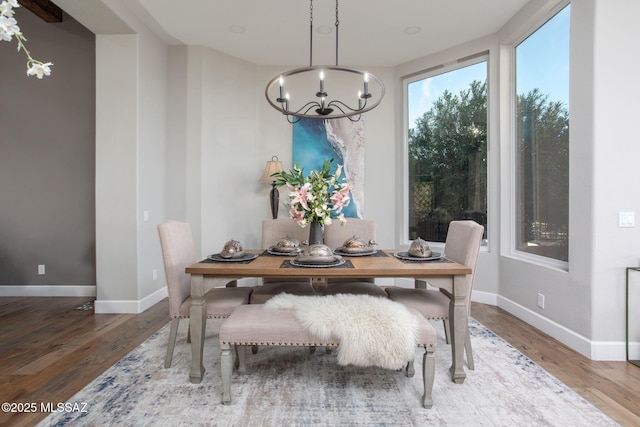 dining space featuring an inviting chandelier, baseboards, and wood finished floors