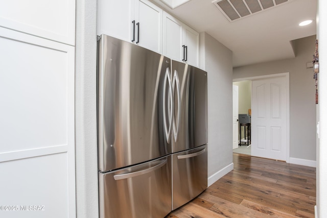 kitchen with visible vents, baseboards, white cabinetry, freestanding refrigerator, and light wood finished floors