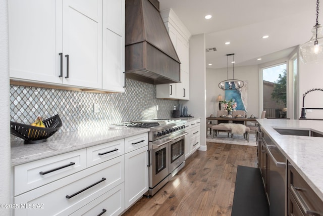 kitchen with appliances with stainless steel finishes, pendant lighting, white cabinetry, and custom exhaust hood