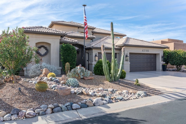 view of front of property with a garage, concrete driveway, a tile roof, and stucco siding