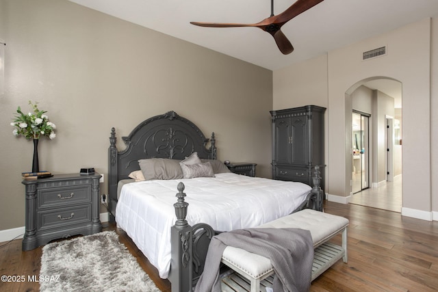 bedroom with arched walkways, dark wood-style flooring, visible vents, and baseboards