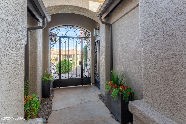 view of exterior entry with a gate and stucco siding