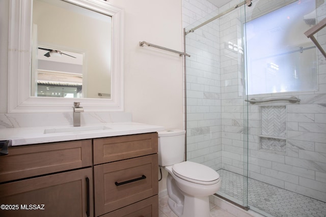 bathroom featuring vanity, a shower stall, and toilet