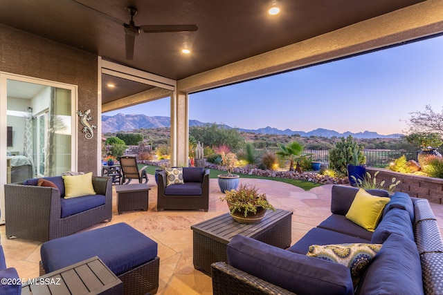 view of patio / terrace featuring an outdoor hangout area, ceiling fan, fence, and a mountain view