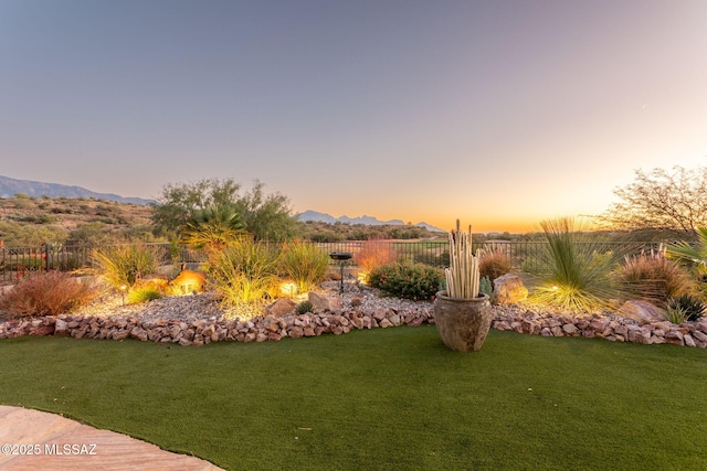 yard at dusk featuring fence and a mountain view