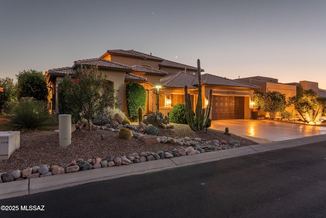 view of front facade featuring concrete driveway, an attached garage, a tile roof, and stucco siding