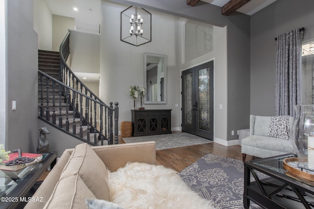 living room featuring baseboards, a towering ceiling, dark wood-style floors, stairs, and french doors