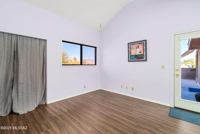 spare room featuring dark wood-type flooring and vaulted ceiling