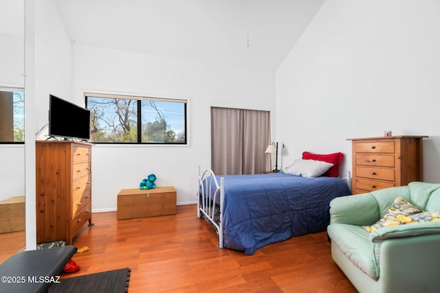 bedroom with wood-type flooring, multiple windows, and high vaulted ceiling