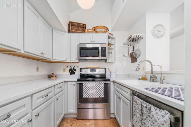 kitchen featuring sink, light tile patterned flooring, white cabinetry, and stainless steel appliances