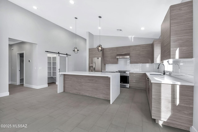 kitchen with a kitchen island, appliances with stainless steel finishes, high vaulted ceiling, decorative light fixtures, and a barn door