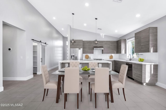 tiled dining area with lofted ceiling, sink, and a barn door