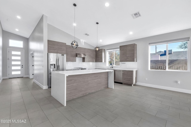 kitchen with vaulted ceiling, hanging light fixtures, a kitchen island, stainless steel appliances, and decorative backsplash