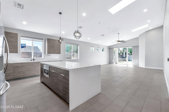 kitchen featuring sink, hanging light fixtures, a kitchen island, vaulted ceiling with skylight, and backsplash