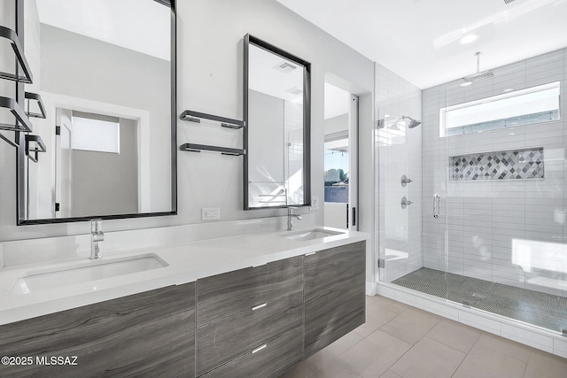 bathroom with a shower with door, vanity, and tile patterned flooring