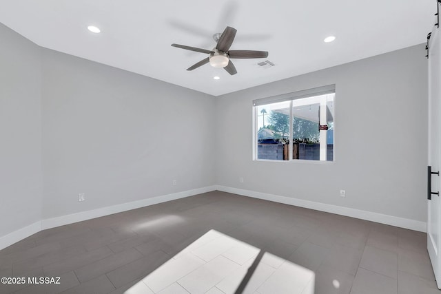 spare room with a barn door and ceiling fan