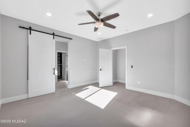 unfurnished bedroom featuring a barn door and ceiling fan