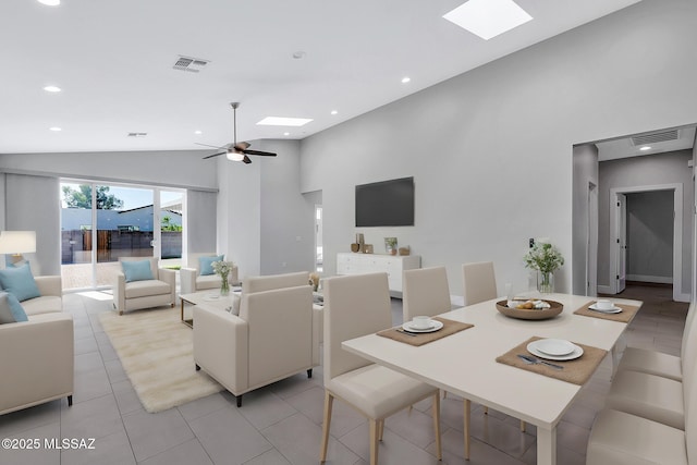 dining area with lofted ceiling with skylight, light tile patterned floors, and ceiling fan