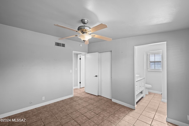 unfurnished bedroom with ceiling fan, ensuite bathroom, a closet, and light tile patterned flooring