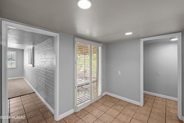 interior space featuring brick wall, a wealth of natural light, and light tile patterned flooring