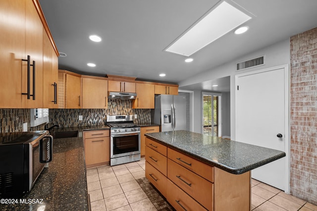 kitchen with sink, stainless steel appliances, a center island, and dark stone countertops