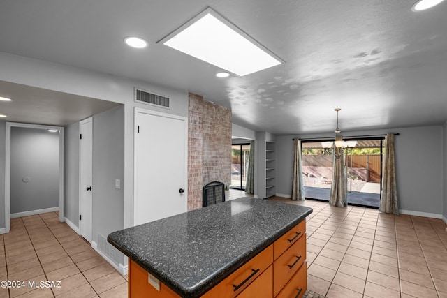 kitchen with a center island, a fireplace, a skylight, hanging light fixtures, and light tile patterned floors