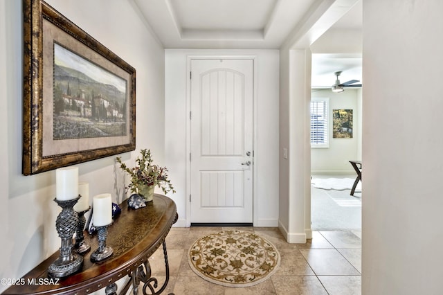 carpeted entrance foyer with a raised ceiling and ceiling fan