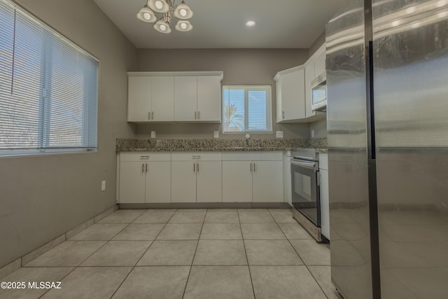 kitchen featuring white cabinetry, appliances with stainless steel finishes, light tile patterned floors, and light stone counters